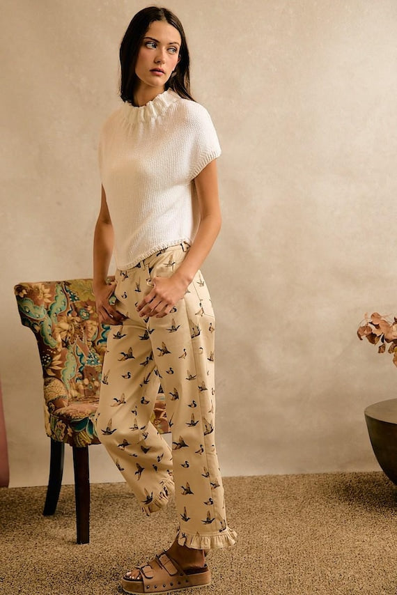 Women's cream wide-leg cotton denim pants with duck print, visible pockets, and ruffle hem, styled for a Cottagecore aesthetic.