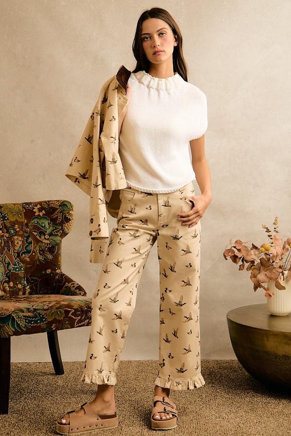 Cream wide leg cotton denim pants with a mallard duck print and a ruffle hem in a cottagecore style.