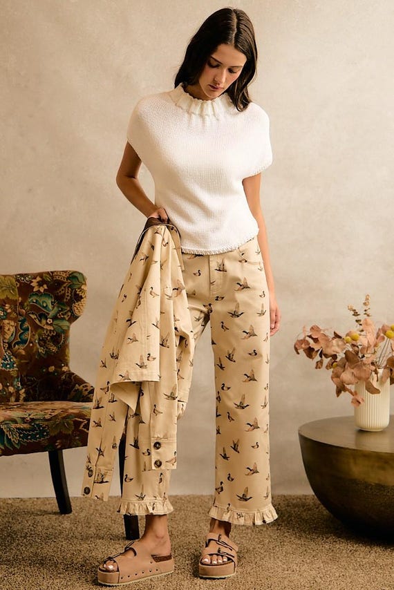 Cream cotton denim wide leg pants featuring a mallard duck print and a ruffle hem, styled with a white knit top.