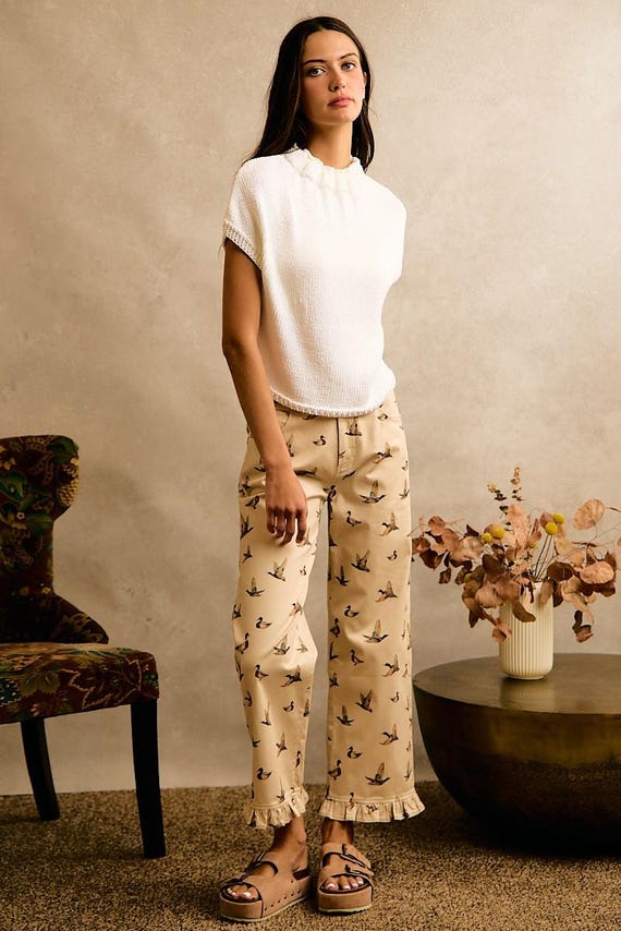 Cream cottagecore wide leg cotton denim pants with a mallard duck print and ruffle hem, paired with a white top.
